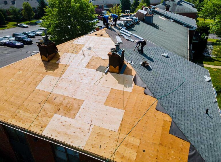 A homeowner taking photos of missing shingles and debris on a residential roof after a storm.