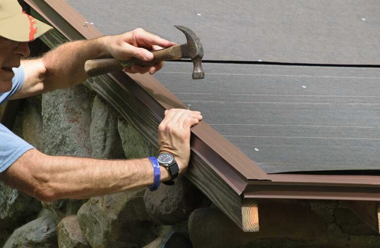 Homeowner examining dark algae streaks and moss on weathered asphalt roof shingles near a gutter.